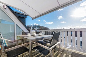 En balkon med et bord, stole og udsigt til himlen og det fjerne landskab.