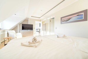 Et moderne hotelværelse med en stor seng, et fjernsyn, et skrivebord og et billede på væggen.