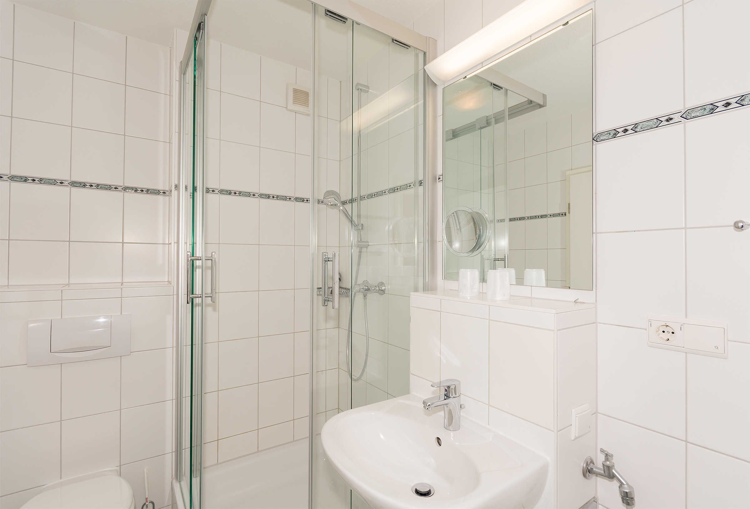 A modern bathroom with a glass-enclosed shower, a white sink, and a mirror above it.
