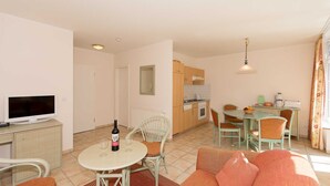 A compact living space with a dining area, kitchenette, and a television. - App. 1 (ground floor) - House Elise (Binz)