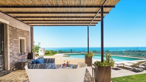 Un espacio exterior cubierto con piscina, un sofá blanco y sillones de descanso.