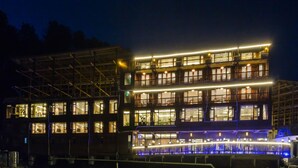 A multi-story hotel with illuminated balconies and a well-lit facade. - Floral Hotel Xijiang Banshan Yunfu (Qiandongnan)