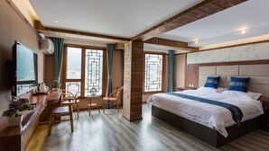 A hotel room with a bed, a desk, and chairs. - Floral Hotel Xijiang Banshan Yunfu (Qiandongnan)