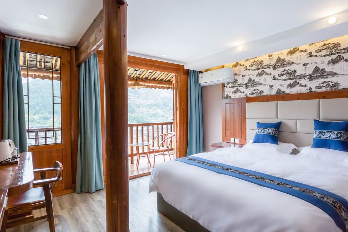 Une chambre d’hôtel comprenant un lit, un bureau avec une chaise et un balcon offrant une vue sur les montagnes.
