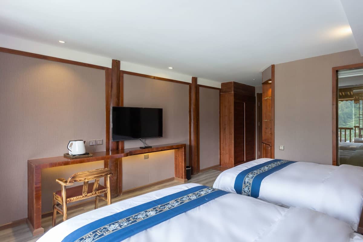 Une chambre d’hôtel avec deux lits, une télévision, un bureau et une vue sur l’extérieur.