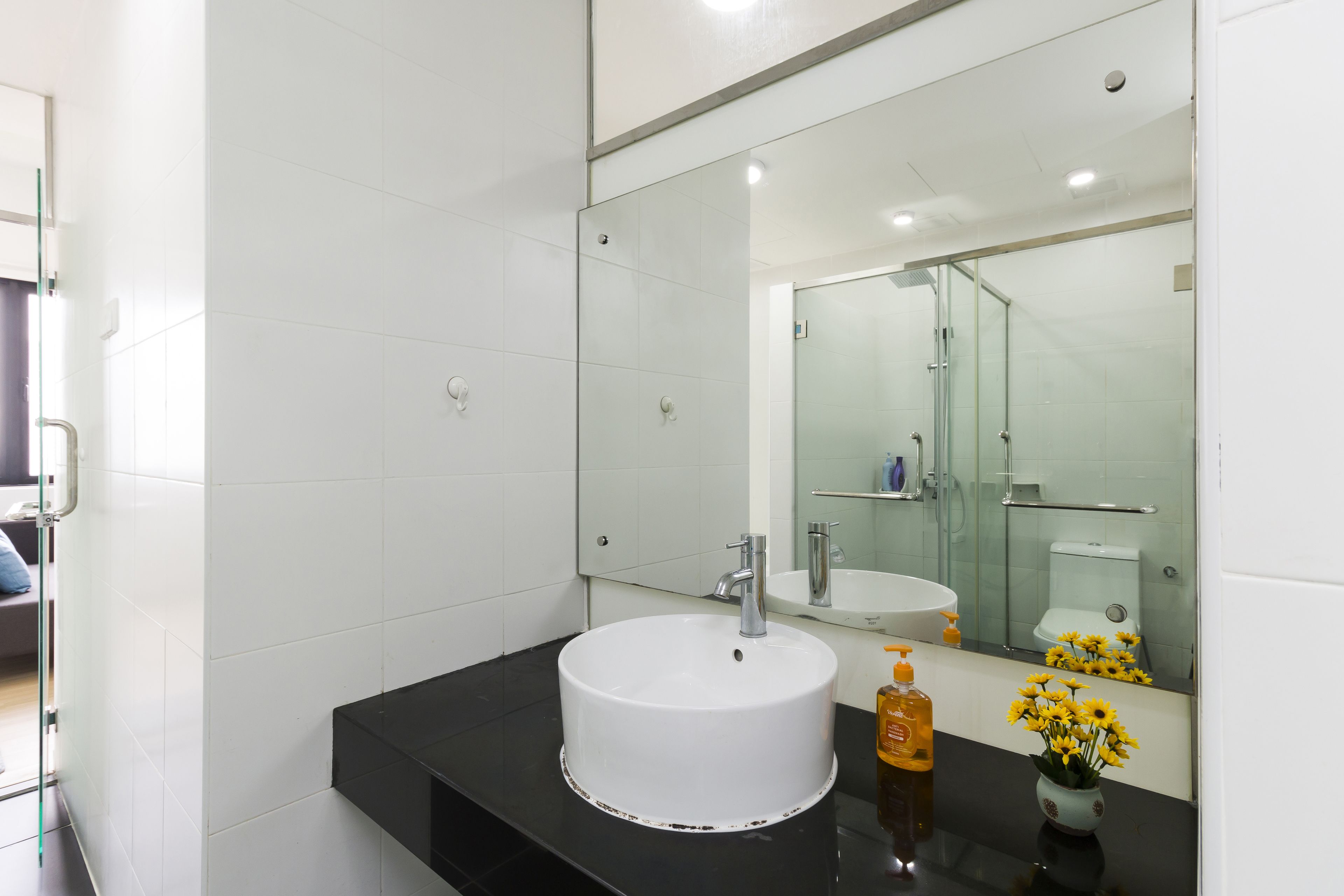 A modern bathroom with a white sink, black countertop, and a large mirror.