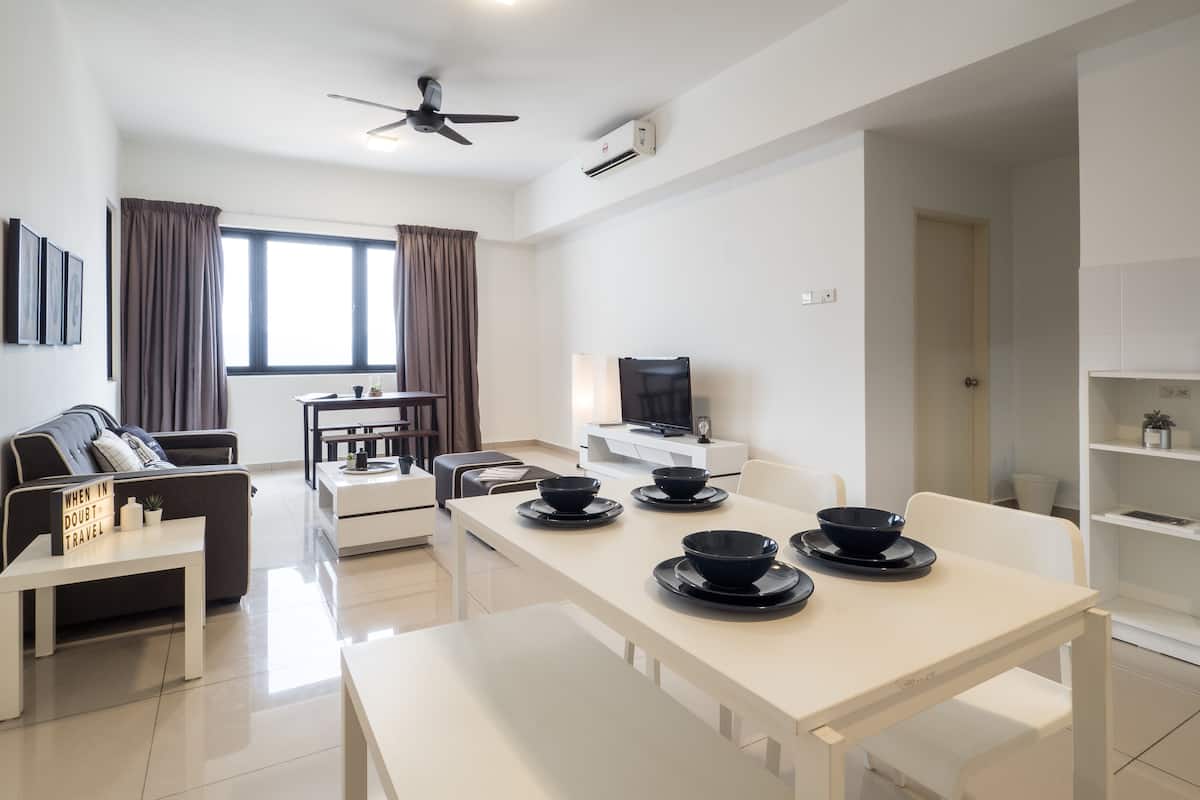 Un salon moderne avec un canapé, une table à manger avec des bols, un téléviseur et un ventilateur de plafond.