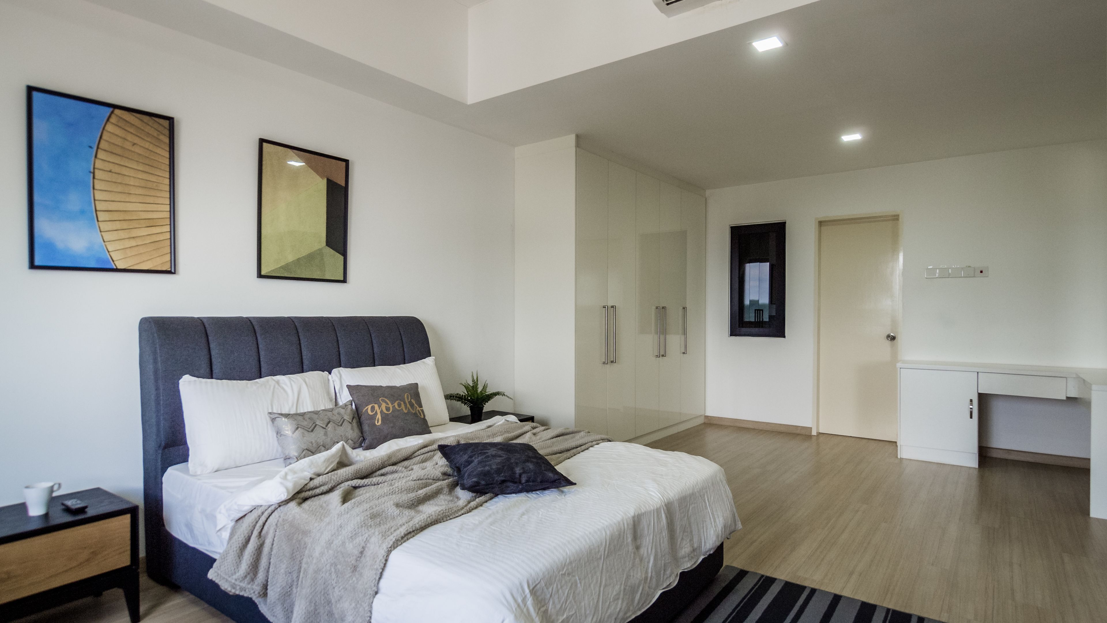 Un dormitorio moderno con cama, mesitas de noche, armario y escritorio.