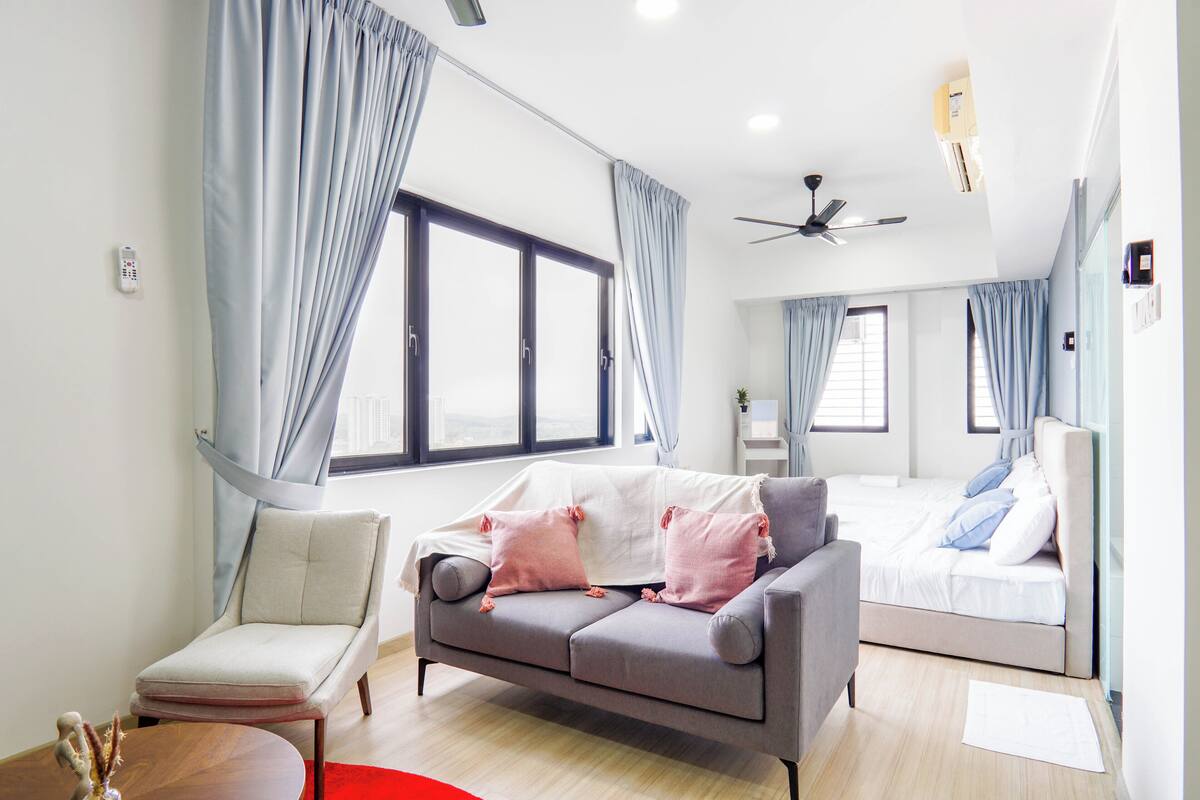 Une chambre moderne avec un canapé gris, un fauteuil blanc et un lit avec une literie bleue et blanche.