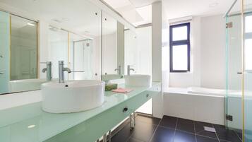 Un baño moderno con dos lavamanos, un espejo grande y una ducha con mampara de vidrio.
