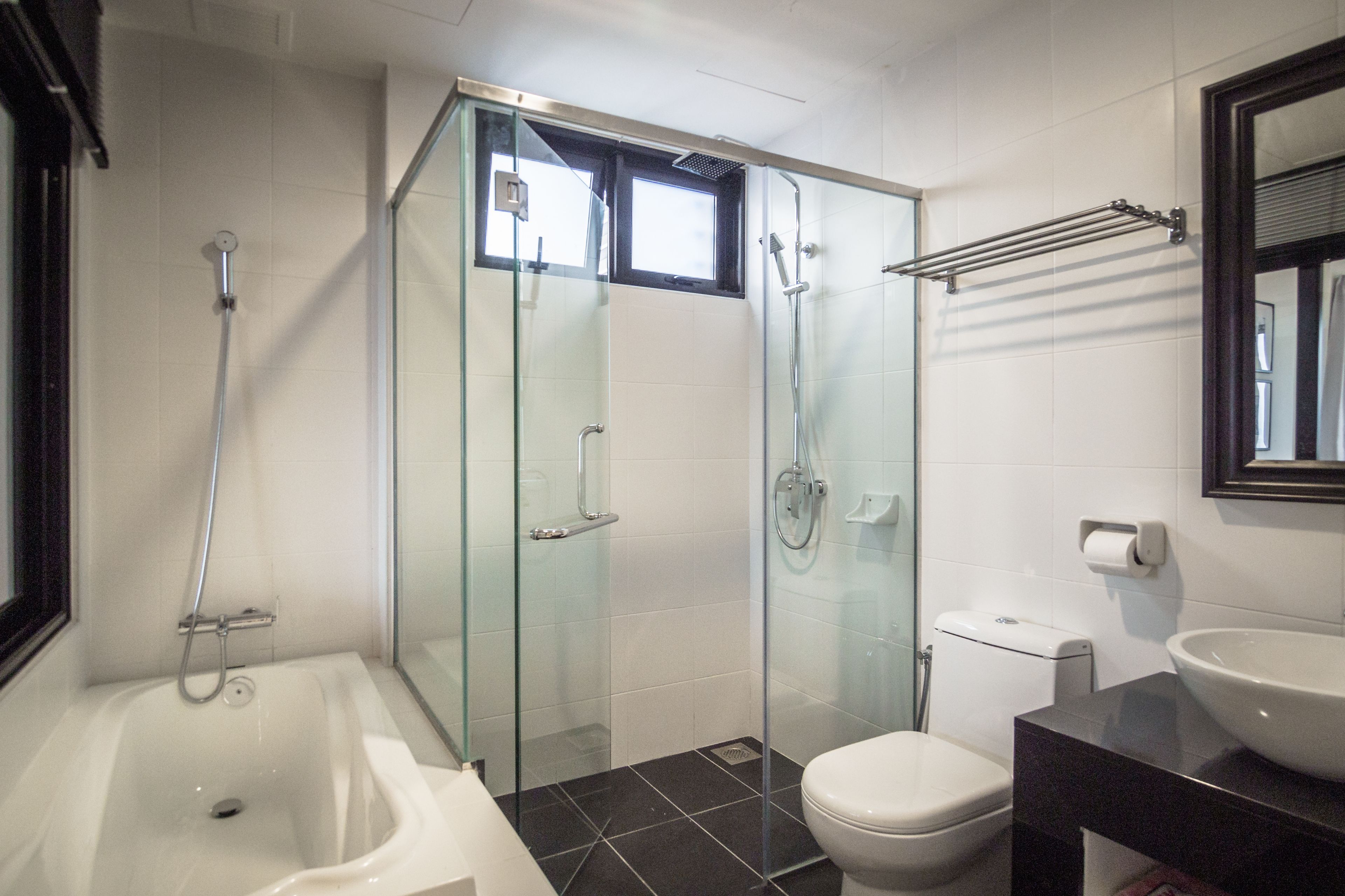 A modern bathroom with a glass-enclosed shower, a bathtub, a toilet, and a sink.
