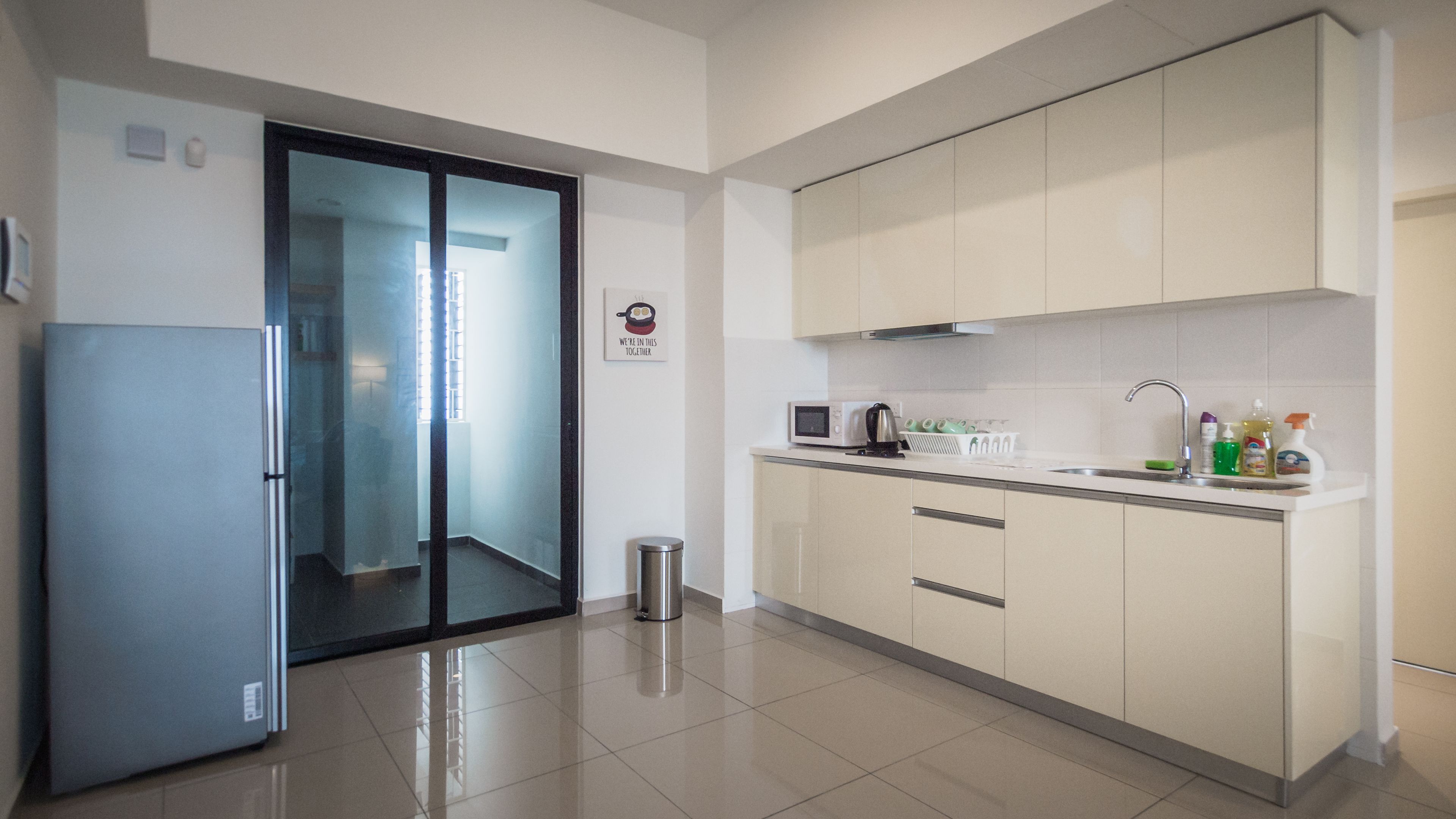 A modern kitchen with a refrigerator, microwave, sink, and cabinets.