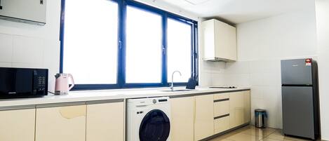 Une cuisine compacte équipée d’un lave-linge, d’un four à micro-ondes et d’un réfrigérateur.