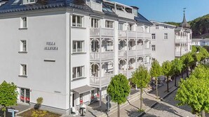 Un hôtel à plusieurs étages doté de balcons, un ciel dégagé et une église en arrière-plan.
