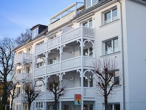 Een meerlaags gebouw met balkons, ramen en een heldere lucht.