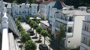 Une vue de rue avec des bâtiments, des arbres et des voitures garées.
