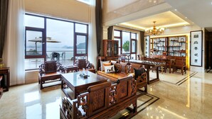 A spacious room with large windows, wooden furniture, and a chandelier.