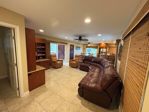 A spacious living area with a sectional sofa, a dining table, and a kitchen in the background.