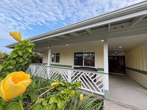 A building with a covered porch, a white railing, and a window with a view of the sky.