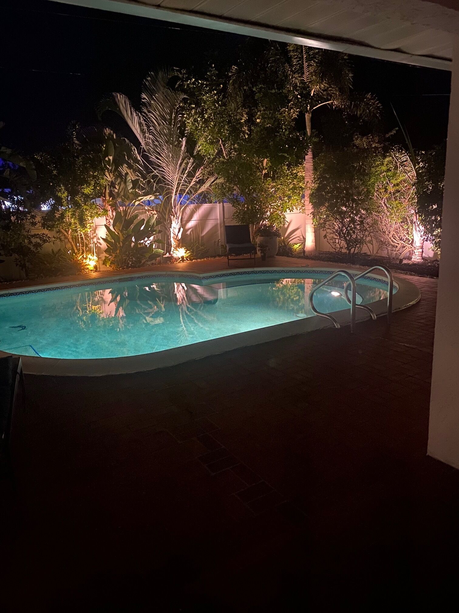 Une piscine avec un toboggan intégré, entourée d’une végétation luxuriante et agrémentée d’une chaise.