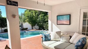 Un espacio exterior techado con un sofá de mimbre, una piscina y un letrero que dice 'No Diving'.