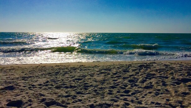Una playa con arena y olas bajo un cielo despejado.