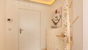 A hallway with a white door, a painting on the wall, and a wooden staircase. - Villa Allegra - 2-room-App. for 1-4 persons (20) - Villa Allegra (Binz)
