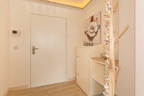 Ein Flur mit einer weißen Tür, einem Bild an der Wand und einer Holztreppe.