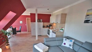 A modern apartment with a grey sofa, a dining area, and a kitchen.