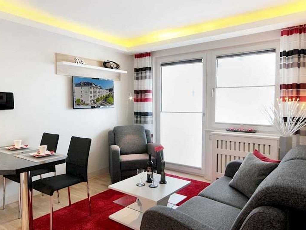 Una sala moderna con sofá, mesa de comedor con sillas, mesa de centro, chimenea y un amplio ventanal con cortinas.