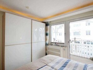 Una camera da letto con un letto, un termosifone, una finestra e vista sugli edifici esterni.