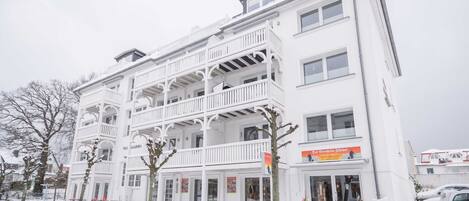 A multi-story building with balconies, a storefront, and a sign that reads 'Hotel.'