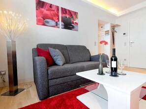 Ein modernes Wohnzimmer mit einem grauen Sofa, einem weißen Couchtisch und einem roten Teppich.