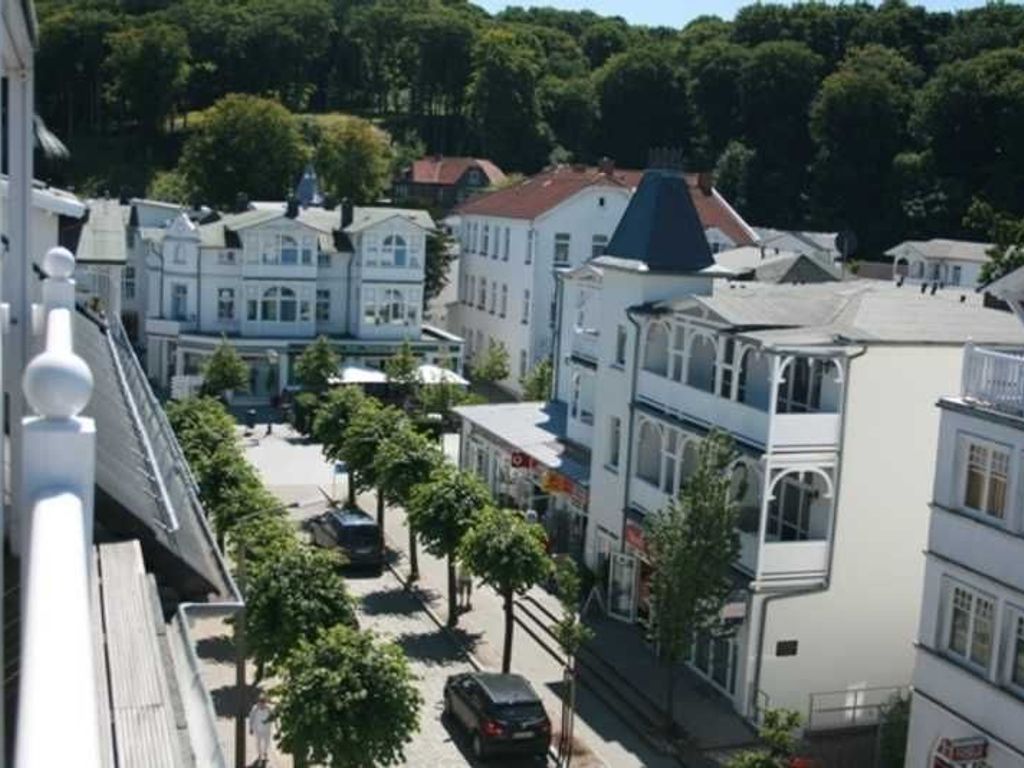A street view with buildings, trees, and parked cars.