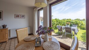 A dining area with a table set for two, featuring woven placemats, a vase with flowers, and a hanging light fixture. - La Casa vacation apartment Kormoran - Holiday apartment Kormoran (Steinberg)