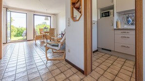 A spacious room with a dining area, a kitchen with modern appliances, and a large sliding glass door leading to a garden. - La Casa vacation apartment Kormoran - Holiday apartment Kormoran (Steinberg)