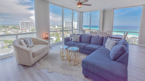A spacious living room with a large window offering a view of the ocean and cityscape. - BOOK YOUR BEACH VACATION! Penthouse Unit with Stunning Views of Destin! (Destin)