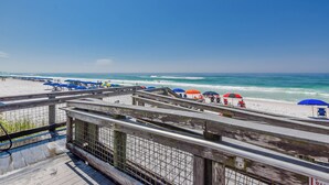 A beach with a wooden boardwalk, umbrellas, and a clear view of the ocean. - BOOK YOUR BEACH VACATION! Penthouse Unit with Stunning Views of Destin! (Destin)