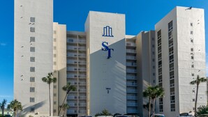 A multi-story hotel with a prominent 'ST' logo on the facade, balconies on each floor, and palm trees in the foreground. - BOOK YOUR BEACH VACATION! Penthouse Unit with Stunning Views of Destin! (Destin)