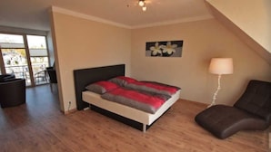 A bedroom with a bed, a chair, a lamp, and a window. - Apartment 7 - Holiday apartments Jack & Richies (Greifswald)