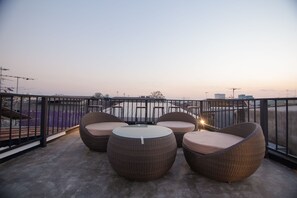 Una terraza en la azotea con mobiliario de mimbre y vistas al horizonte de la ciudad.