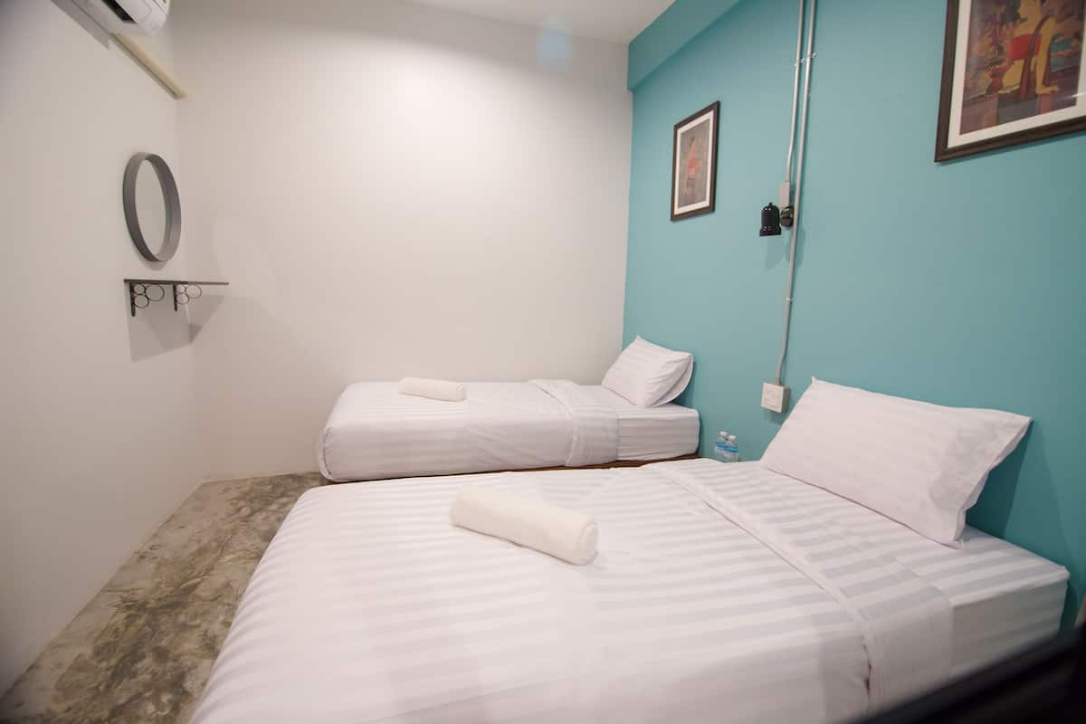 Une chambre d’hôtel avec deux lits, une petite étagère avec un miroir et un tableau au mur.