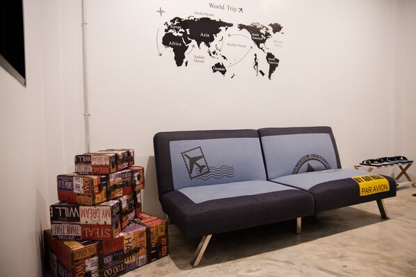 Um quarto com um mapa-múndi na parede, um sofá e uma pilha de livros.