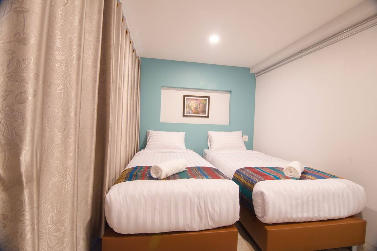 Une chambre d’hôtel avec deux lits, un tableau au mur et un rideau.