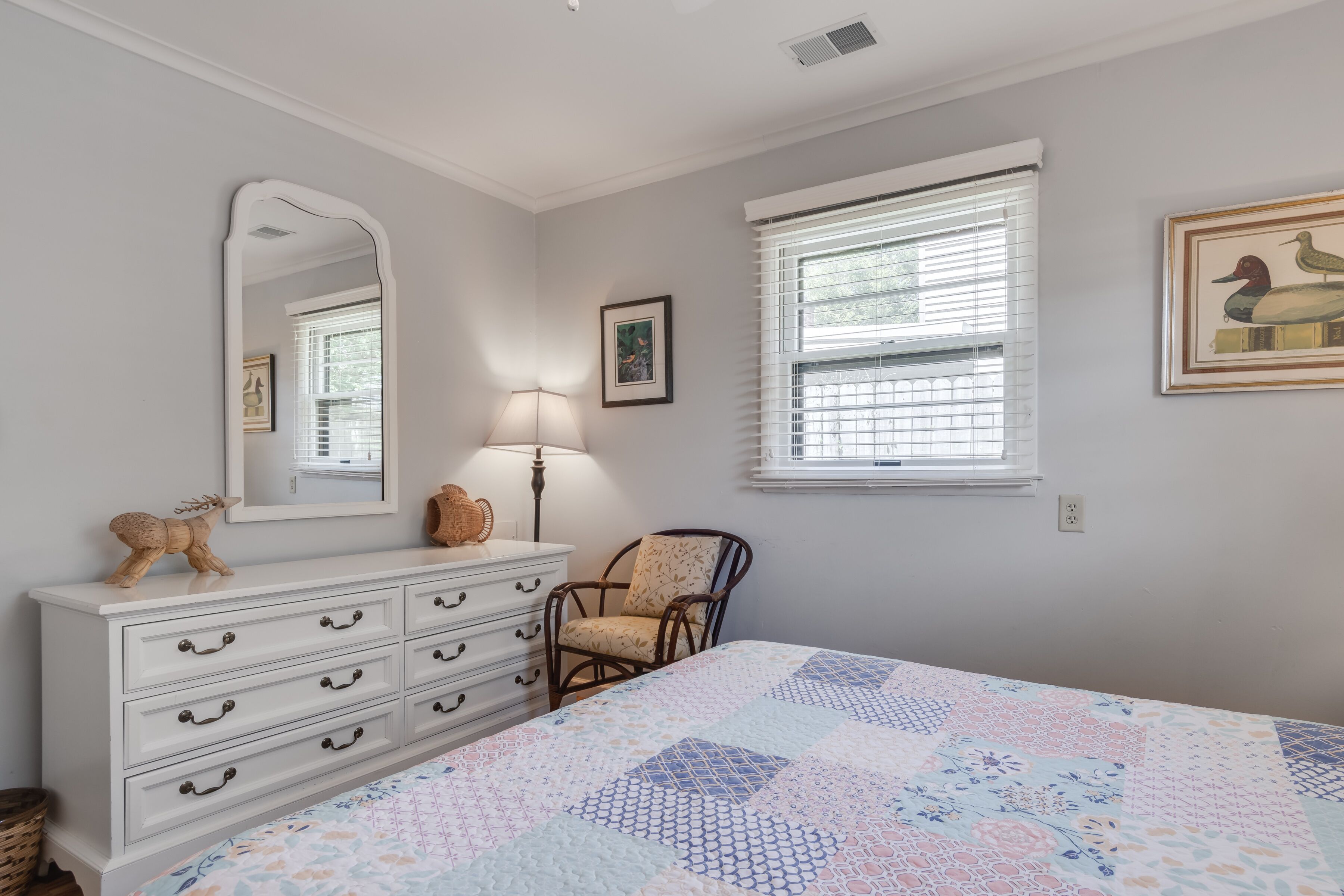 Un dormitorio con cama, cómoda, silla y ventana con persianas.