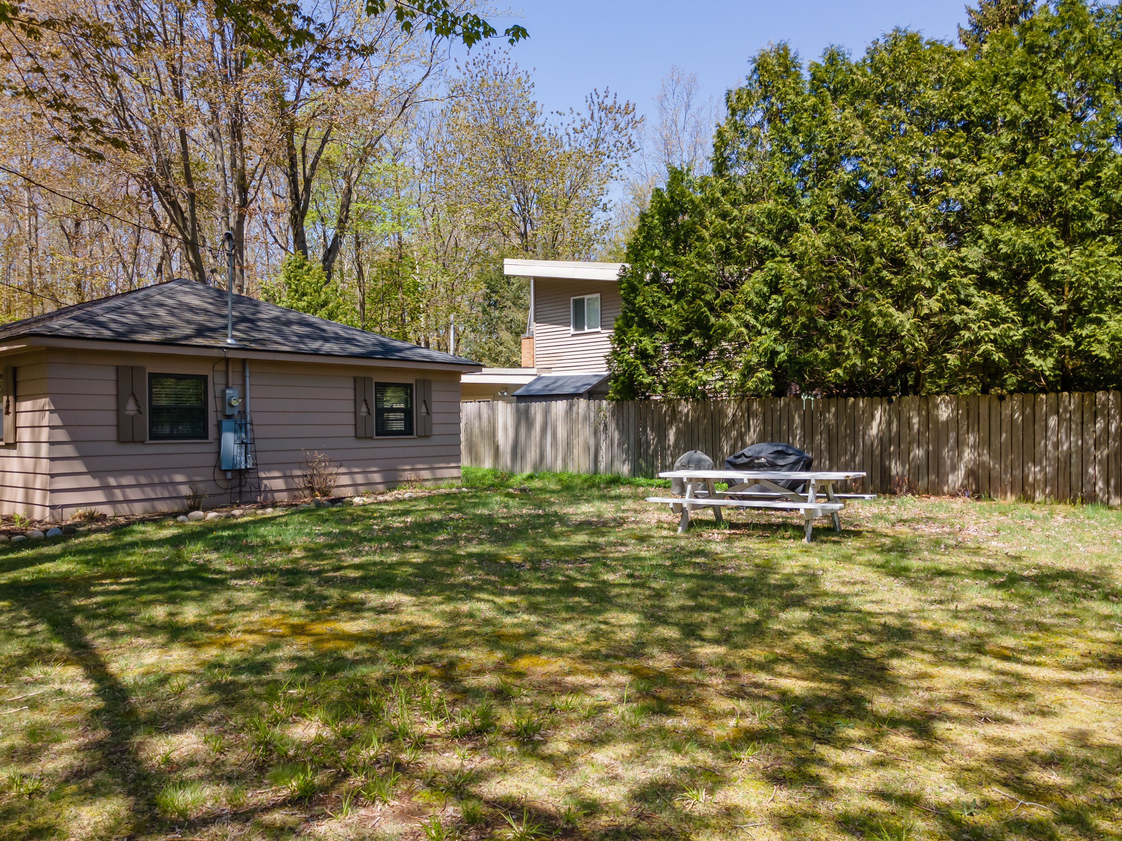 A backyard with a picnic table, a small house, and a wooden fence.