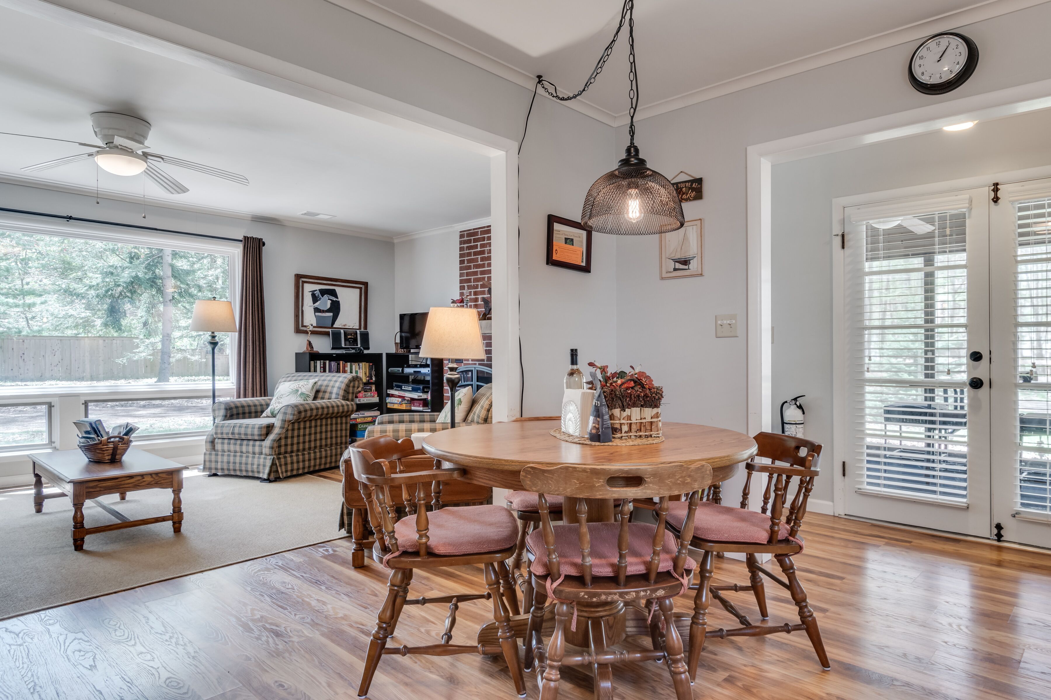 A dining area with a round wooden table, six chairs, and a hanging light fixture.