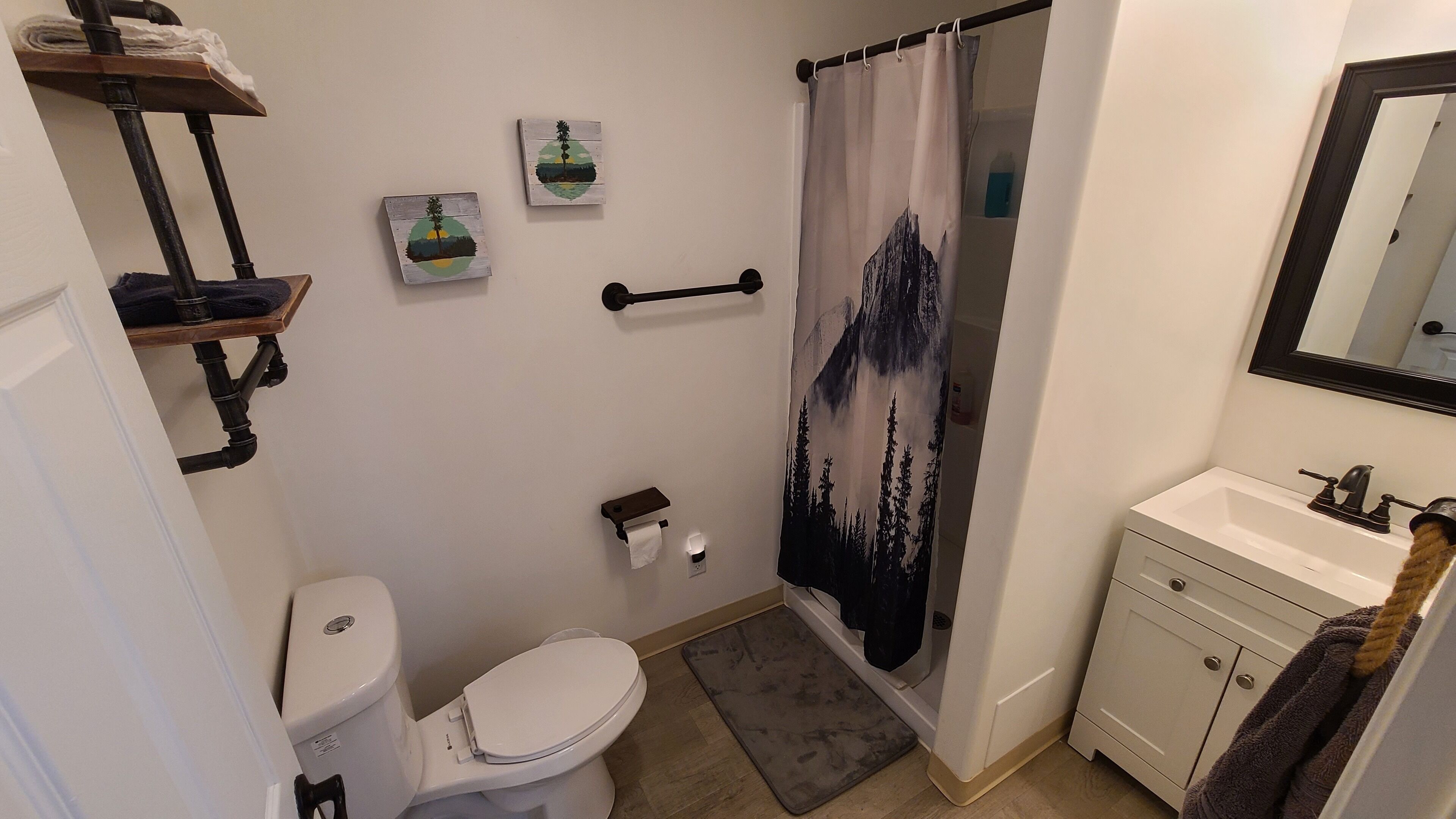A bathroom with a toilet, sink, shower curtain, and towel rack.