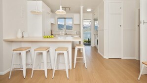 A modern kitchen with a central island, bar stools, and a view of the outdoors.