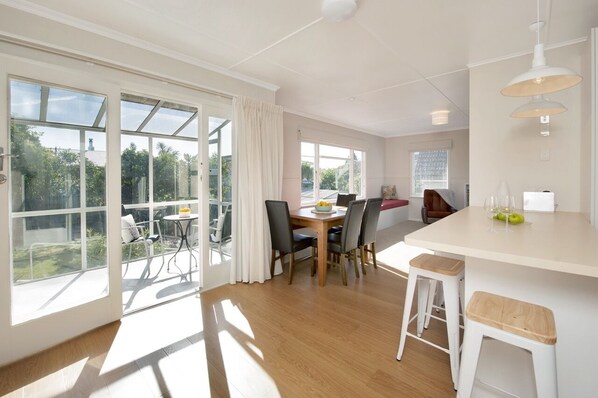 A bright kitchen with large windows, a dining area with chairs, and a bar area with stools. - Monaco Waterside Magic - Holiday Home with Magnificent Water Views (Monaco)